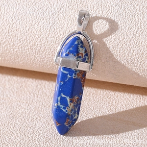 Macro shot of blue hexagonal column stone pendant with silver clasp on beige texture