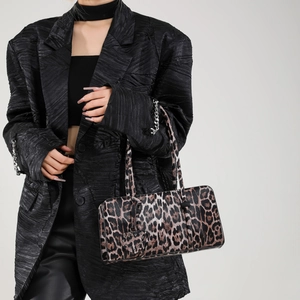 Leopard print handbag with heart charm shown on model in a modern grey background