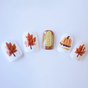 Short square press-on nails with autumn maple leaf, pumpkin, and corn harvest designs