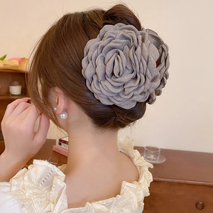 Close-up of a large grey fabric flower hair claw clip on an elegant hairstyle