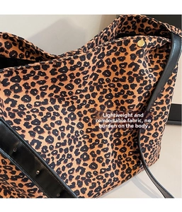 Close-up of leopard print canvas tote with black leather strap and gold metal button