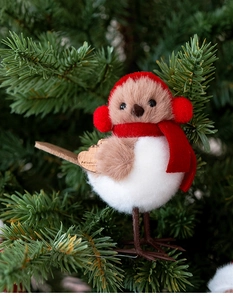 Detail of a Christmas bird ornament with a red knit hat perched on pine branches