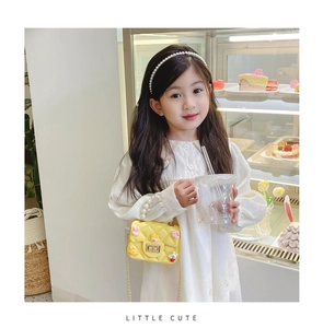 Girl's yellow crossbody bag featuring quilted texture and cartoon charms with gold chain