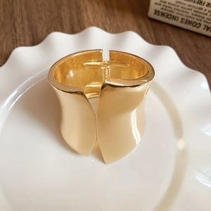 Detailed view of wide irregular gold metal cuff bracelet with polished mirror finish