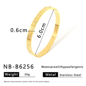 Detailed view of gold stainless steel bangle with flower patterns and small crystals