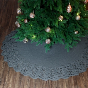 Deep grey knitted Christmas tree skirt with hollow wavy edge on warm wooden floor
