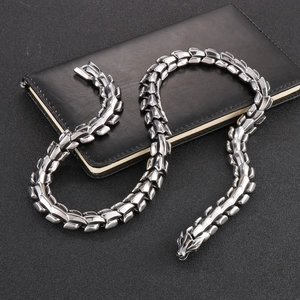 Polished silver dragon bone chain necklace displayed on a black notebook surface