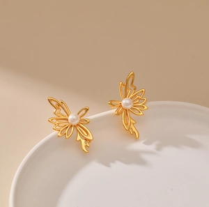 Dettaglio degli orecchini a farfalla placcati oro 18K con perla su piatto di ceramica