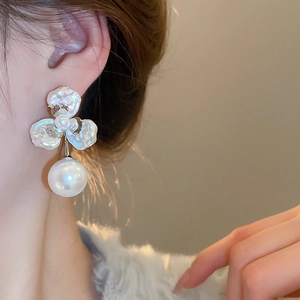 Close-up of elegant flower pearl earrings on model showing delicate petal texture