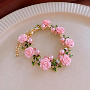 Macro detail of a pink rose pearl bracelet with gold leaves and sparkling crystals