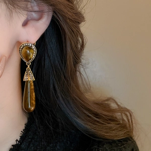 Close-up of long amber resin teardrop earrings with crystals on a female model