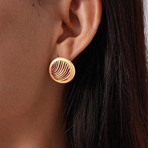 Close-up of vintage golden round stud earrings with textured wave design on a model