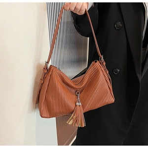 Detailed view of caramel brown pleated handbag with fringe tassel and zipper closure