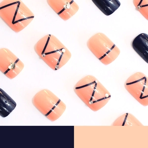Short square press-on nails set in peach orange and navy blue with rhinestones