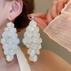 Macro shot of long shell petal fringe earrings with zircon inlay worn by model