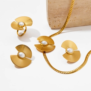 Vintage-Set aus fächerförmiger Goldkette und Ring mit Perlen auf strukturiertem Stein