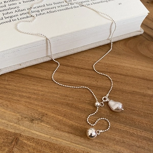 Detailed shot of silver bead chain necklace with pearl pendant on an open vintage book