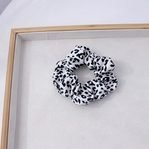 Détail d'un chouchou imprimé léopard noir et blanc sur un plateau à bijoux en velours