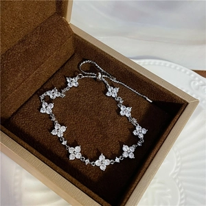 Detailed view of silver flower bracelet with sparkling crystals on brown velvet display