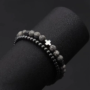 Detail view of double bead bracelets featuring a metal cross and lava tiger eye stones