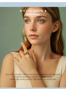 Close-up of minimalist golden teardrop open ring worn on finger against green background