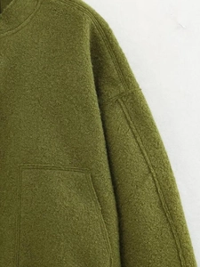 Close-up detail of olive green bomber jacket showing thick textured wool fabric and pocket
