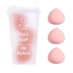 Trois éponges de maquillage roses en forme de pêche dans un gobelet givré pour le teint