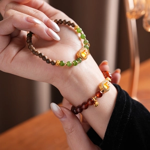 Detail of red and green beaded bracelets with golden gourd charms on model wrist