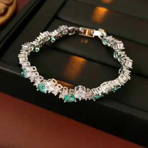 Detail of silver twisted bracelet with green emerald-cut stones and white zircon crystals