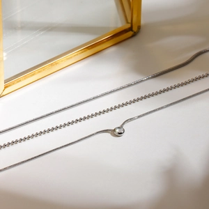 Three-layer silver titanium steel necklace with clear zircon pendant on sleek light background