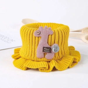 Detail of yellow knit baby neck warmer featuring a handmade pink giraffe decoration
