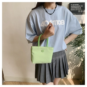 Détail du sac seau en nylon vert clair avec logo m et tenue d'été décontractée