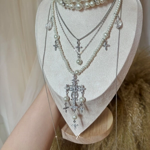 Close-up of layered baroque pearl cross necklace with crystal teardrop charms on a bust