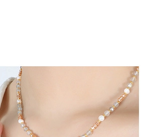 Détail du collier de perles blanches et cristaux facettés de couleur pêche poli