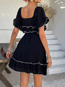 Rear view of black mini dress featuring ruffled sleeves and contrast white piped edges