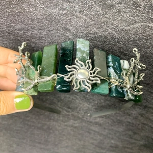 Detail of green crystal crown headband with silver sunburst and branch accents
