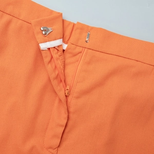 Detail view of orange linen skirt waist featuring a metal hook, zipper, and fine stitching