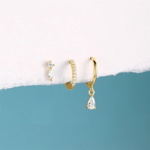 Detailed close-up of gold star earrings set with white zircons on a creative paper edge