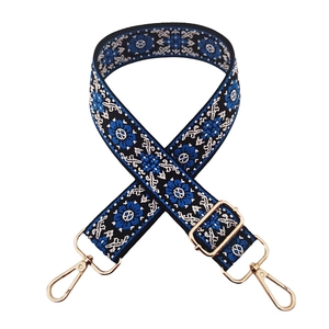 Ethnic wide bag strap with blue floral embroidery and gold metal hardware on white background