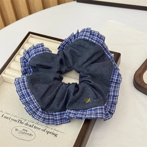 Detailed shot of a blue denim hair scrunchie with plaid ruffle edge and metal button