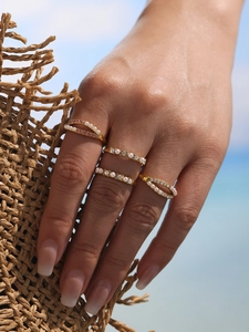 Close-up of a 4-piece gold ring set with pearls and pink crystals on a model's hand
