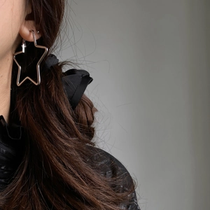 Close-up of minimalist silver star hoop earrings worn to show modern hollow design