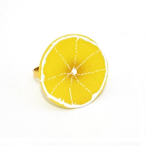 Vue détaillée du rond de serviette citron 3D avec support doré sur tissu blanc