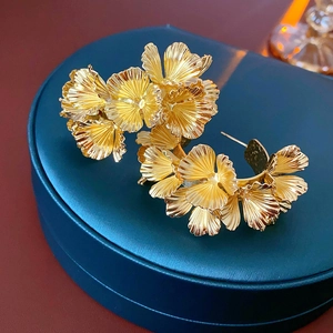 Detailed view of gold flower earrings placed on a navy blue jewelry box with a red base