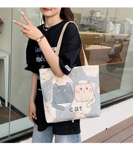 Detailed view of beige canvas tote bag with cat print on a female model outdoors