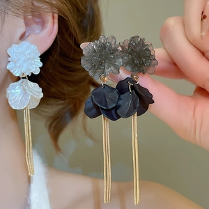 Macro detail of long floral tassel earrings with acrylic petals and golden chains