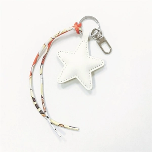 Close-up of star-shaped leather keychain with printed ribbon and silver metal clip