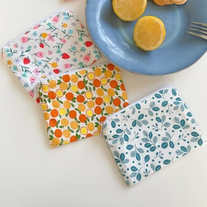 Detail of floral and fruit print cotton coin purses with top zipper closure on a table