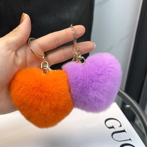 Close-up of orange and purple heart-shaped faux fur pom pom keychains with gold rings