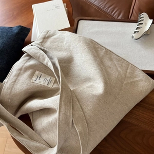 Détail d'un sac cabas en toile beige avec texture épaisse et étiquette tissée décorative